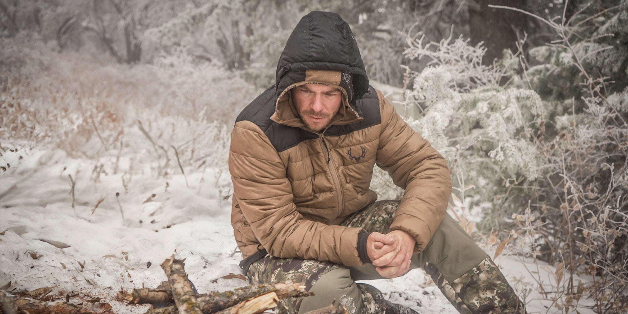 A hunter sitting by a fire in the snow in the high country